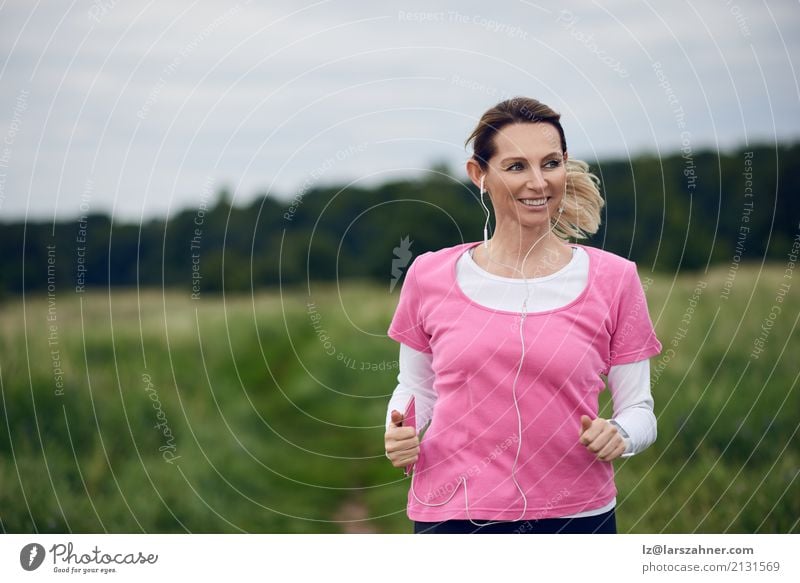 Cheerful woman running through field Lifestyle Face Summer Music Sports Jogging PDA Woman Adults 1 Human being 30 - 45 years Nature Autumn Blonde Fitness