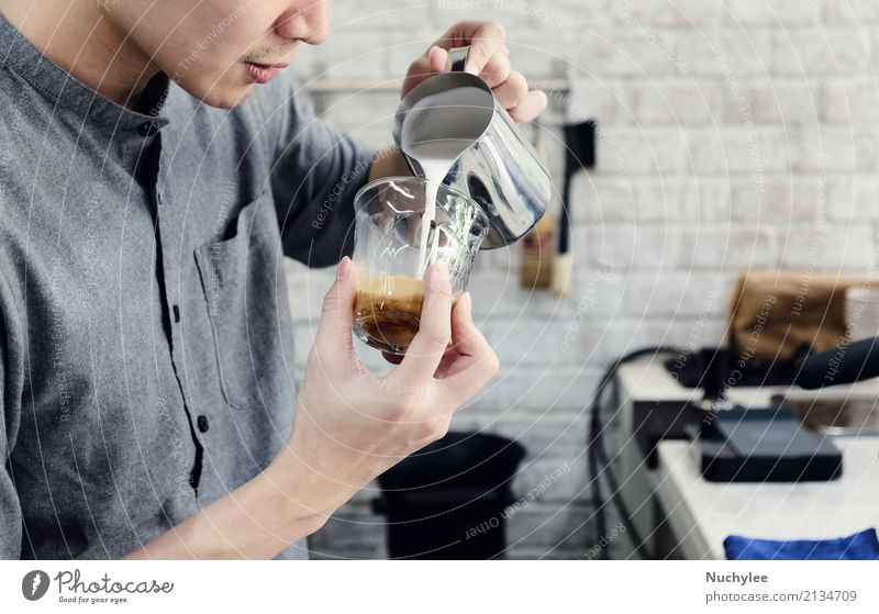 Hipster barista pours milk for making cappuccino or latte coffee in the cafe rustic cocktail beverage handsome occupation young male art business cafeteria