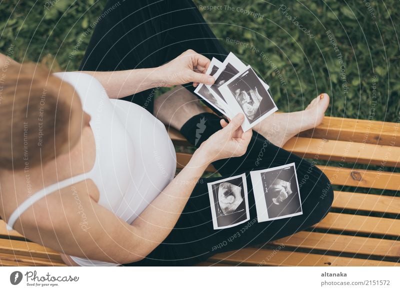 pregnant woman sitting on the bench and loocking ultrasound scan at the day time. Concept of happy expectation. Lifestyle Happy Beautiful Body Child Human being