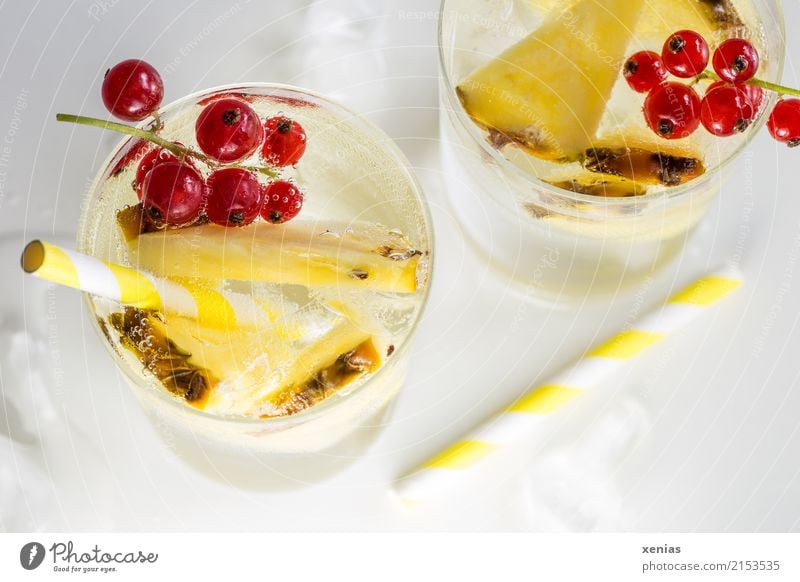 Refreshing drink with pineapple, currants, yellow drinking straws and ice cubes on a white background Beverage Cold drink Pineapple Redcurrant Ice cube