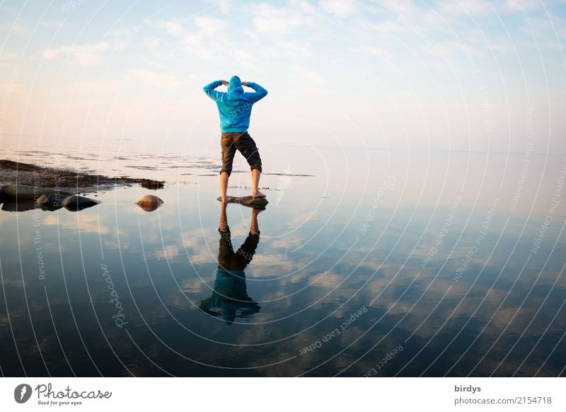 Man with turquoise hoody stands on a rock in the smooth sea and looks into the distance Masculine Androgynous 1 Human being 30 - 45 years Adults 45 - 60 years