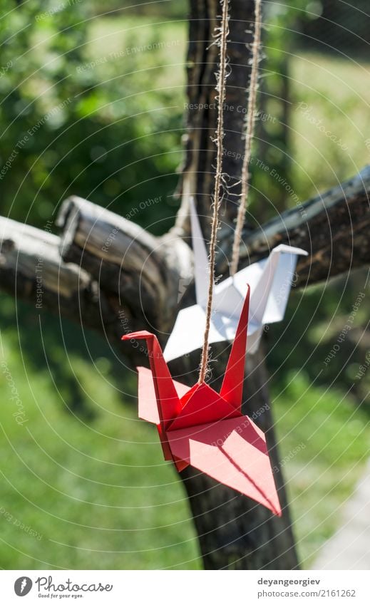 Origami cranes in the garden. Figures of paper in the nature. Beautiful Summer Sun Garden Decoration Craft (trade) Art Nature Tree Bird Paper Green Pink Red