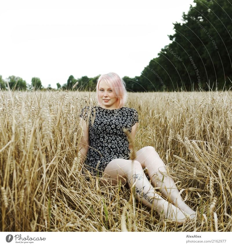 Portrait of a young, tattooed woman sitting barefoot in a summer dress in a field Grain luck already Well-being Trip Young woman Youth (Young adults) Face Legs