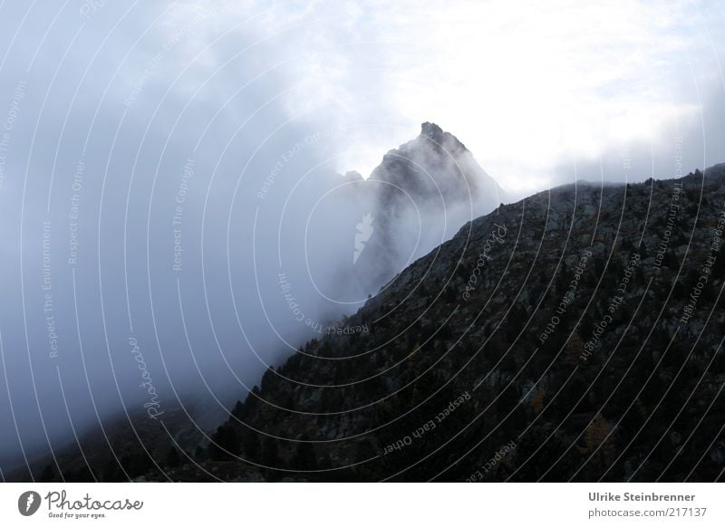 Mountain peak rises from wall of fog Vacation & Travel Landscape Elements Fog Alps Peak Threat Dark Wall of fog Stone Tall Upward Steep Force of nature Nature