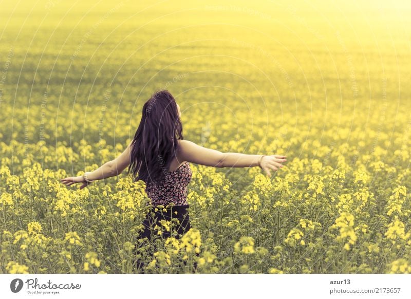 Beautiful young woman in summer on yellow meadow from rape to horizon. Pretty girl with zest for life enjoys the sunshine break and life. Rest and recharge energy from time stress in environment and nature idyll. Outstretched arms.