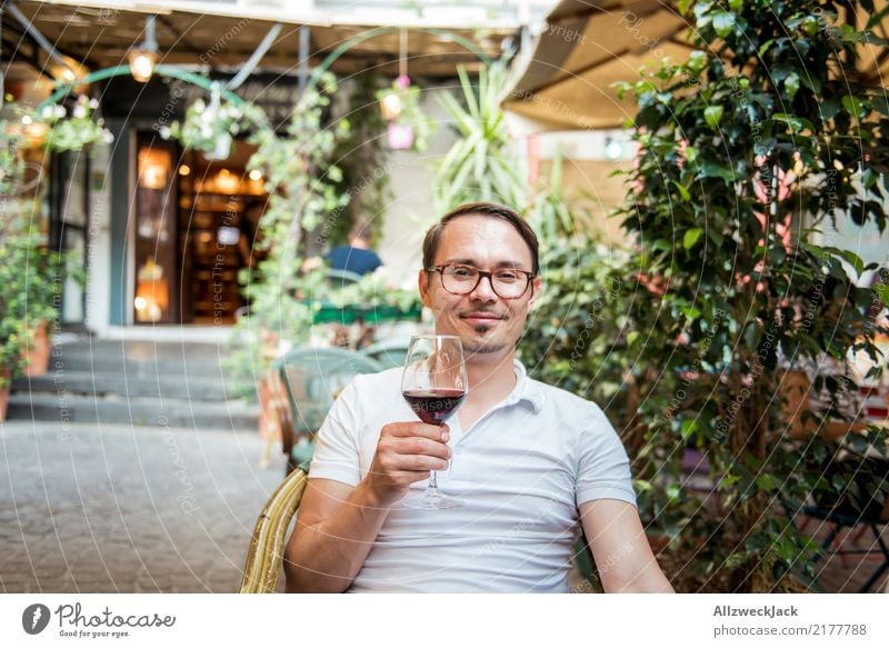 Man with wine glass sits in chair and is satisfied 1 Person Young man Sit Day Exterior shot Warmth Summer Wine Wine glass Red wine Alcoholic drinks Drinking