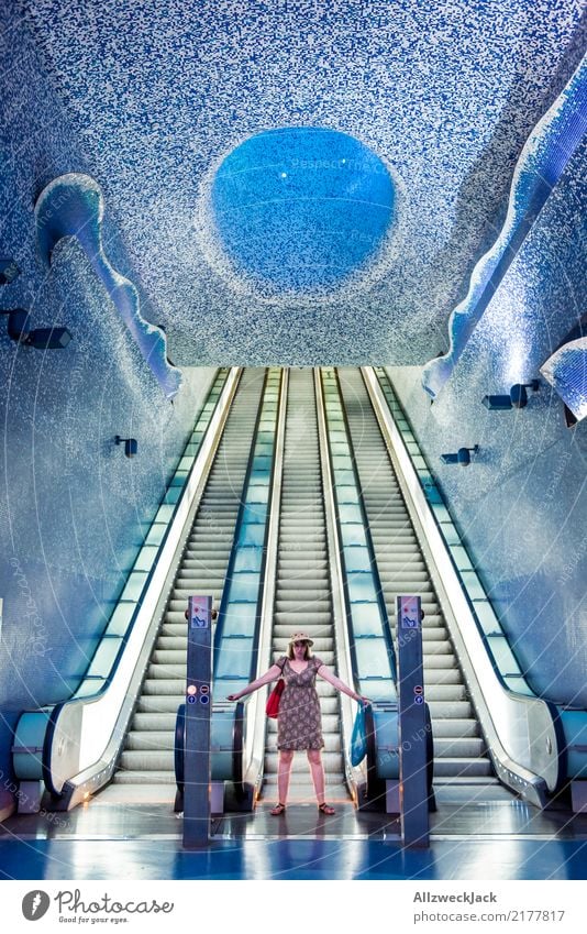 Woman standing or an escalator in the subway station Feminine Hat Dress Artificial light Underground Subsoil Escalator Stairs Tile Futurism Underwater photo