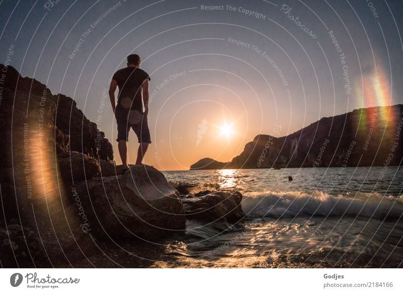 Young man standing on a rock looking at the sea at dusk Human being Masculine Man Adults 1 30 - 45 years Nature Water Cloudless sky Sunrise Sunset Summer