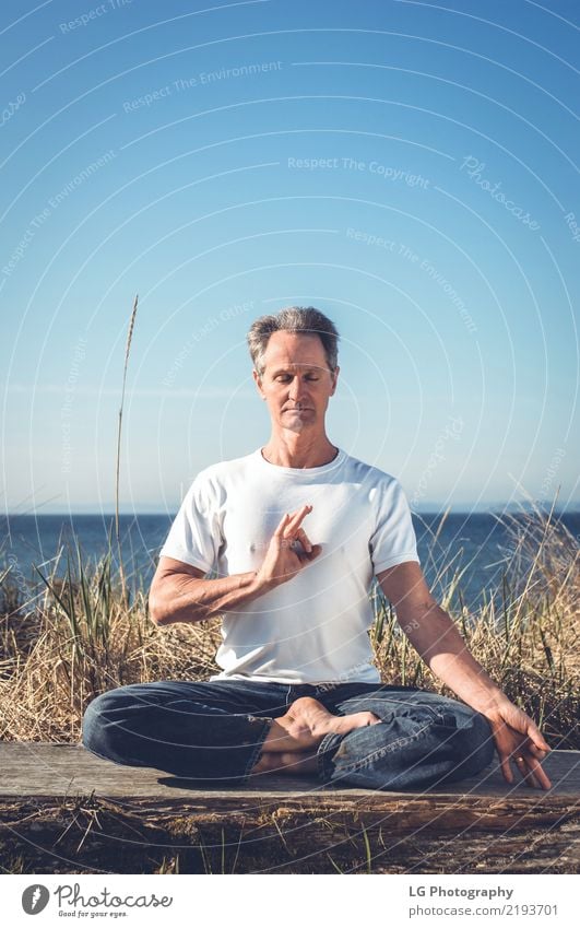 Man sitting in a relaxed yoga pose at the beach. Relaxation Meditation Sun Yoga Adults Old Sit Natural Power Serene 50-60 years Action color image