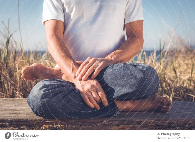 Man sitting in a relaxed yoga pose at the beach. Relaxation Meditation Sun Yoga Adults Old Sit Natural Power Serene 50-60 years Action color image