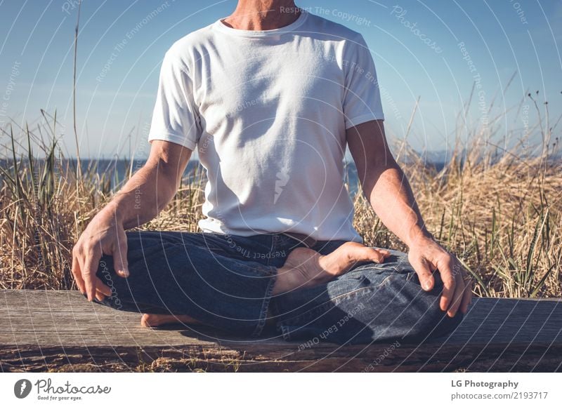 Man sitting in a relaxed yoga pose at the beach. Relaxation Meditation Sun Yoga Adults Old Sit Natural Power Serene 50-60 years Action color image