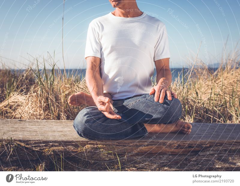 Man sitting in a relaxed yoga pose at the beach. Relaxation Meditation Sun Yoga Adults Old Sit Natural Power Serene 50-60 years Action color image