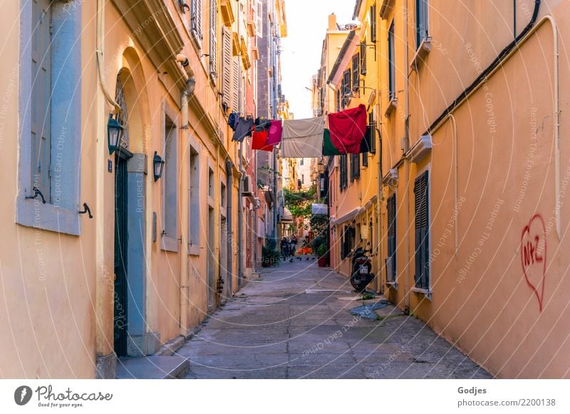 Laundry hanging on a line in an alley from house to house Sky Kérkira Corfu Capital city Old town Alley Facade Balcony Window door Lamp Passenger traffic