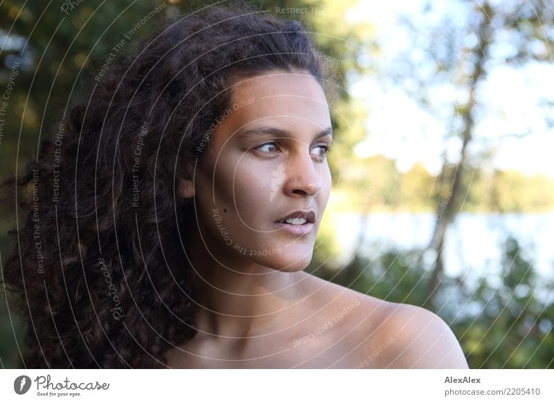 Young beautiful woman with long curly dark hair looks to the side standing in nature pretty Hair and hairstyles Life Well-being Young woman Youth (Young adults)