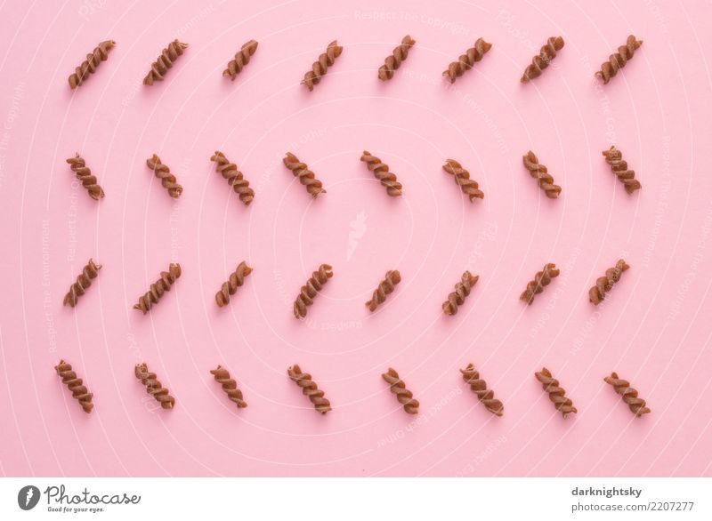 A total of 32 Spirelli pasta, also called spirals or in Italy Fusilli, arranged in a zigzag pattern on a pink background. Food in Italian and orderly arrangement in "German" style.