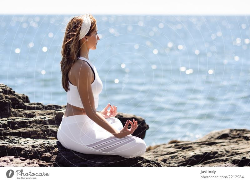 Young woman doing yoga in the beach. Female wearing white sport clothes in lotus figure Lifestyle Beautiful Wellness Relaxation Meditation Summer Beach Ocean