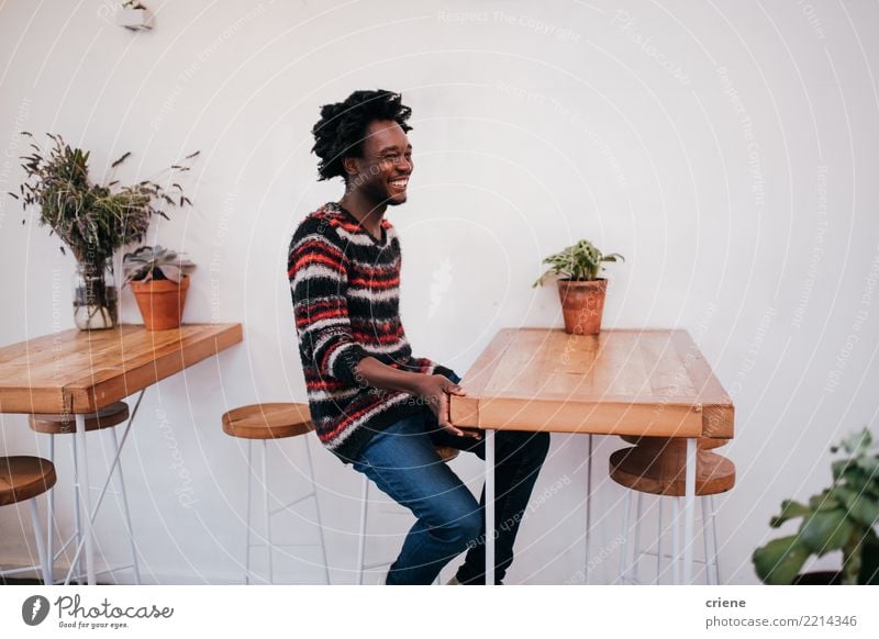 Young happy afro american man sitting in cafe Lifestyle Joy Relaxation Table Restaurant Human being Man Adults Youth (Young adults) Afro Wood Smiling Sit Modern