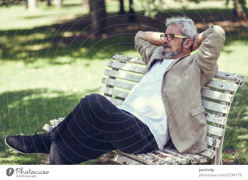 Pensive mature man sitting on a bench in an urban park. Lifestyle Happy Retirement Human being Masculine Man Adults Male senior 1 45 - 60 years