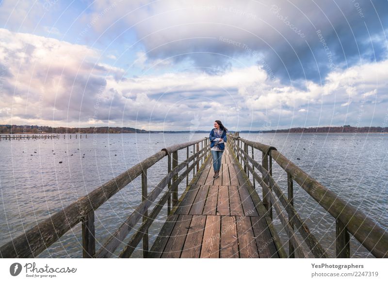 Smiling woman walking on a bridge Vacation & Travel Tourism Freedom Human being Feminine Young woman Youth (Young adults) 1 Nature Horizon Lake Loneliness