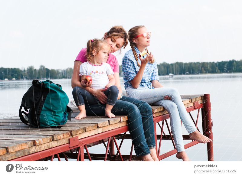 Family spending vacation time together having a snack sitting on jetty over the lake on sunny day in the summertime Joy Happy Relaxation Leisure and hobbies