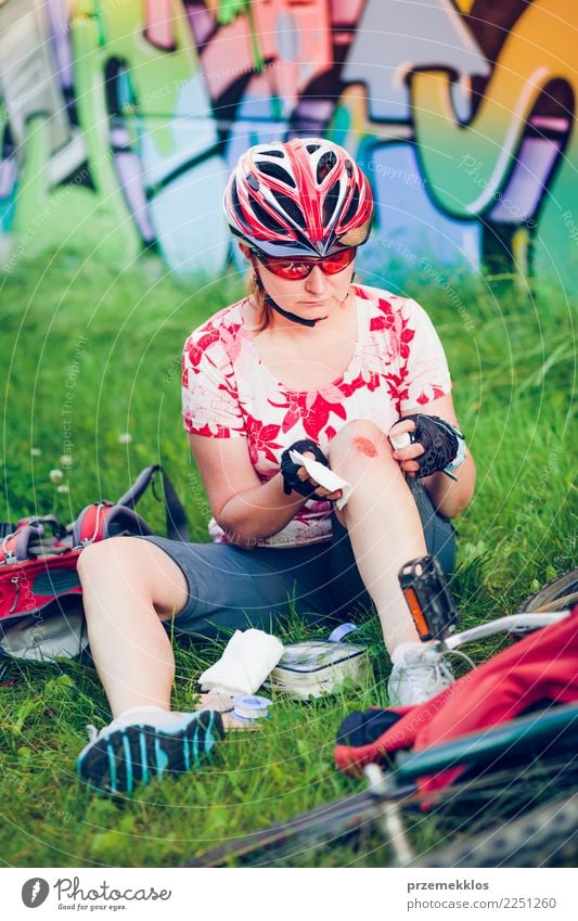 Woman dressing the wound on her knee with medicine in spray Lifestyle Vacation & Travel Summer Sports Cycling Human being Adults Grass Pain accident Action