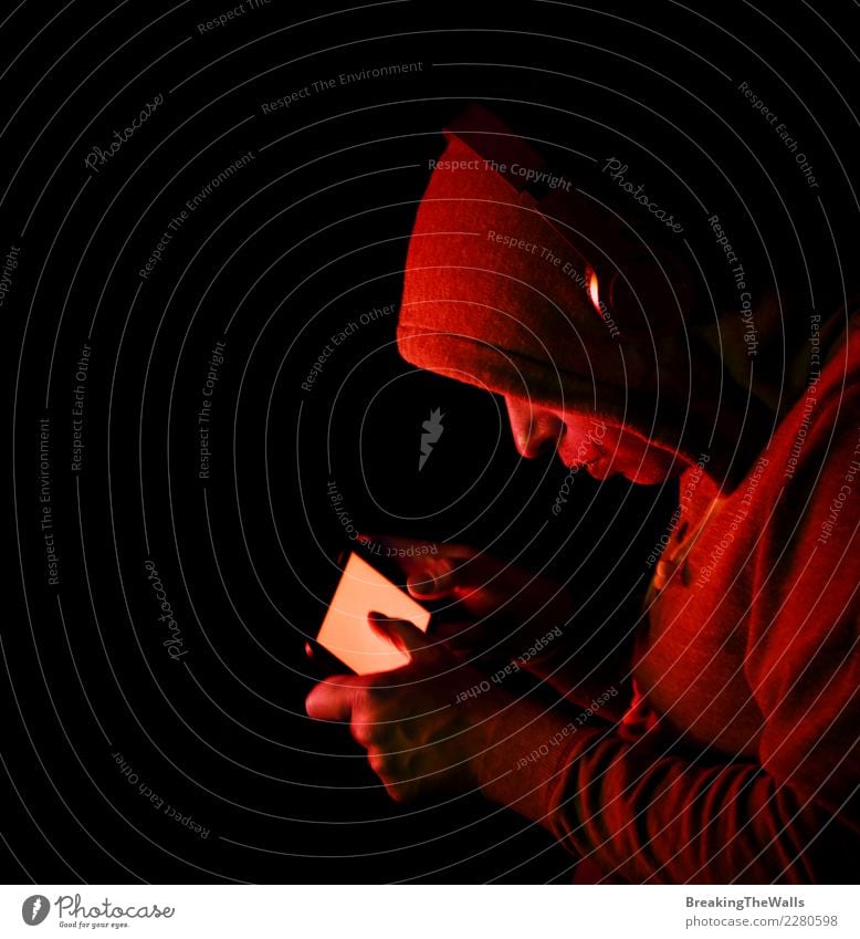 Man in hoodie holding smartphone over black background Lifestyle Leisure and hobbies Playing Computer games Entertainment Music Cellphone Screen