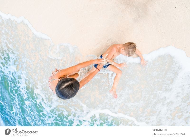 Cute boy and girl having fun on the sunny tropical beach. Lying on sand, wonderful waves around them. View from above Lifestyle Joy Freedom Summer Island Child