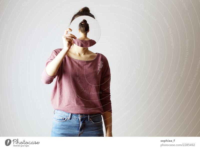 Who am I? Young woman holding a mirror in front of her face. Faceless, identity not recognizable, the mirror is showing her backhead. Hiding her face. who am i