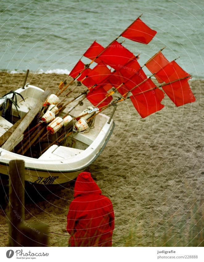 Red on the beach Human being 1 Environment Nature Landscape Climate Coast Beach Baltic Sea Ocean Fishing boat Sit Wait Moody Flag Hooded (clothing) Rain jacket