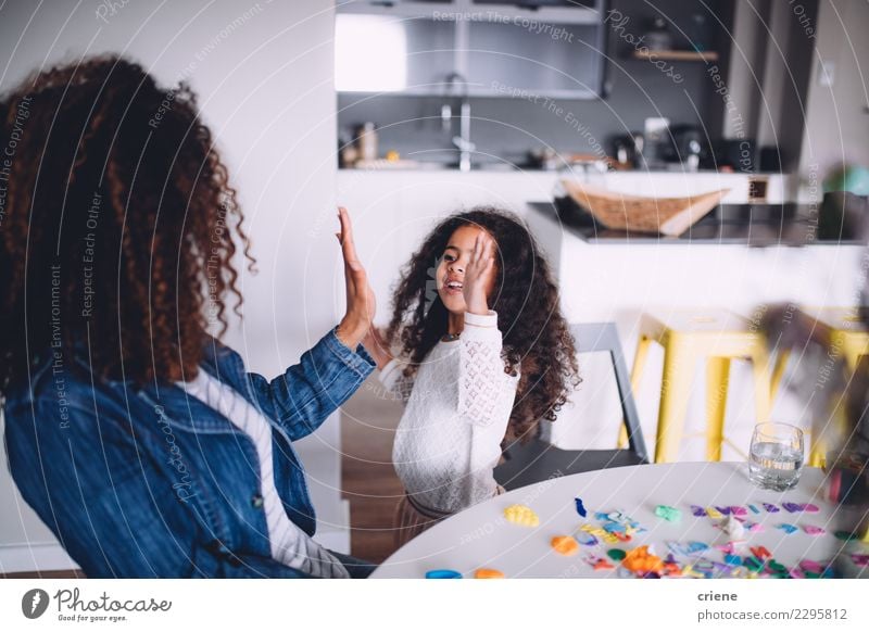 Mother and daughter giving each other high five Joy Happy Playing Table Kindergarten Child School Woman Adults Parents Family & Relations Infancy Paper Pen