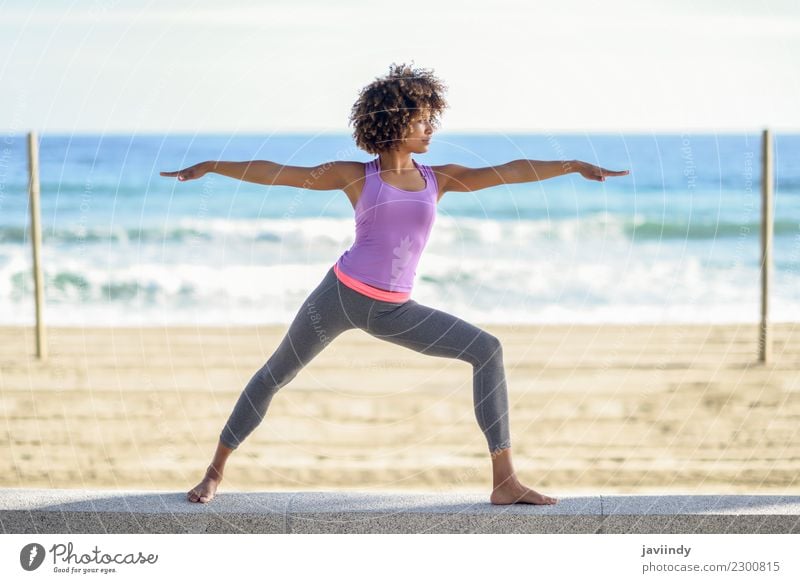 Black woman doing yoga in warrior pose in the beach. Lifestyle Beautiful Body Hair and hairstyles Wellness Relaxation Meditation Leisure and hobbies Beach Ocean