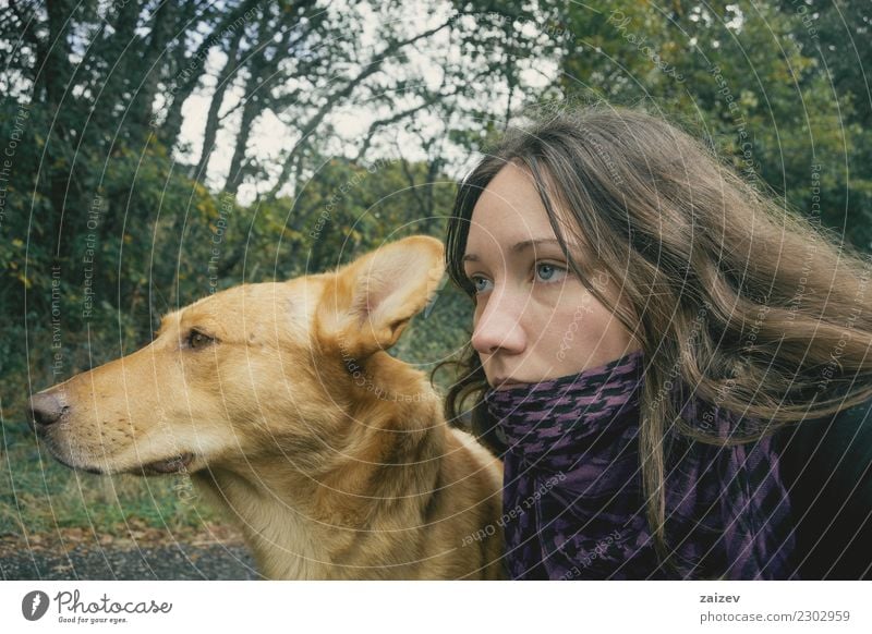 Perro de color marron claro junto a chica de ojos azules y cabello largo mirando juntos hacia adelante, esperando. Lifestyle Beautiful Wellness Relaxation