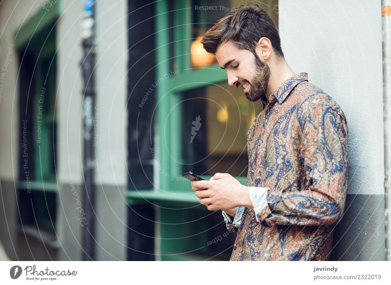 Young smiling man looking at his smartphone in the street Lifestyle Style Beautiful Hair and hairstyles Telephone PDA Human being Masculine Young man