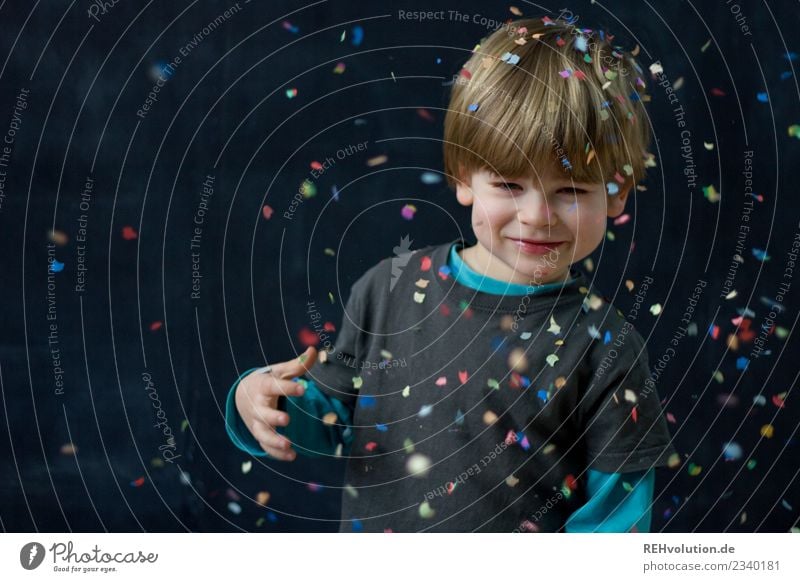 Child stands in a shower of confetti Brash Funny Confetti Authentic Throw Smiling Idea Uniqueness Creativity Neutral Background Happy Joy Human being Playing