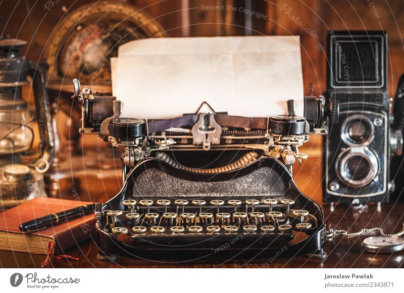 vintage photography still life with typewriter, folding camera, globe map and book on a wood table. White aged antique background black brown business card