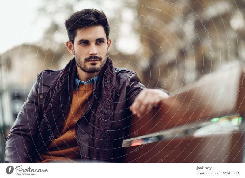 Thoughtful young man sitting on an urban bench Lifestyle Style Beautiful Hair and hairstyles Human being Man Adults Fashion Jeans Sweater Jacket Leather Scarf