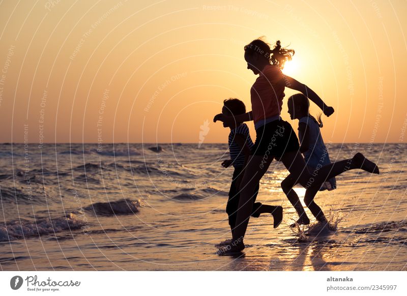 Happy children playing on the beach at the sunset time. Lifestyle Joy Leisure and hobbies Playing Vacation & Travel Trip Adventure Freedom Summer Sun Beach