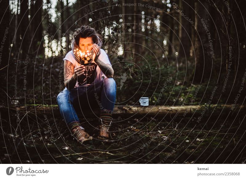 Woman with burning sparkler on a tree trunk in the forest. An enamel cup stands next to her. Cup Lifestyle Harmonious Well-being Senses Relaxation Calm