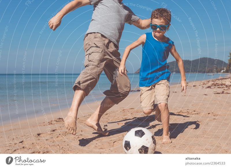 Father and son playing football on the beach at the day time. Concept of friendly family. Lifestyle Joy Happy Relaxation Playing Vacation & Travel Trip