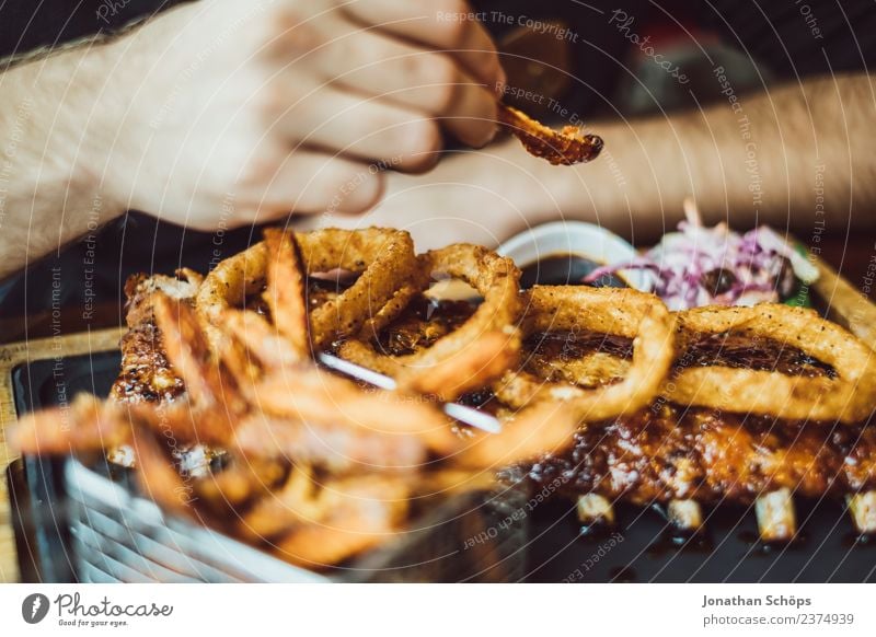 Man in restaurant eating fries with ribs Food Meat French fries Onion ring Lunch Dinner Fast food Overweight Tourism Human being Masculine Life Arm Hand Fingers