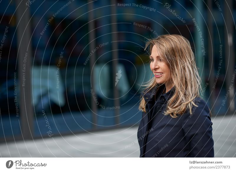 Happy blond woman walking down an urban street Face Business Woman Adults 1 Human being 45 - 60 years Building Street Blonde Smiling Happiness Self-confident