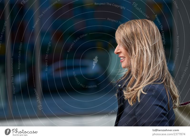 Happy blond woman walking down an urban street Face Business Woman Adults 1 Human being 45 - 60 years Building Street Blonde Smiling Happiness Self-confident