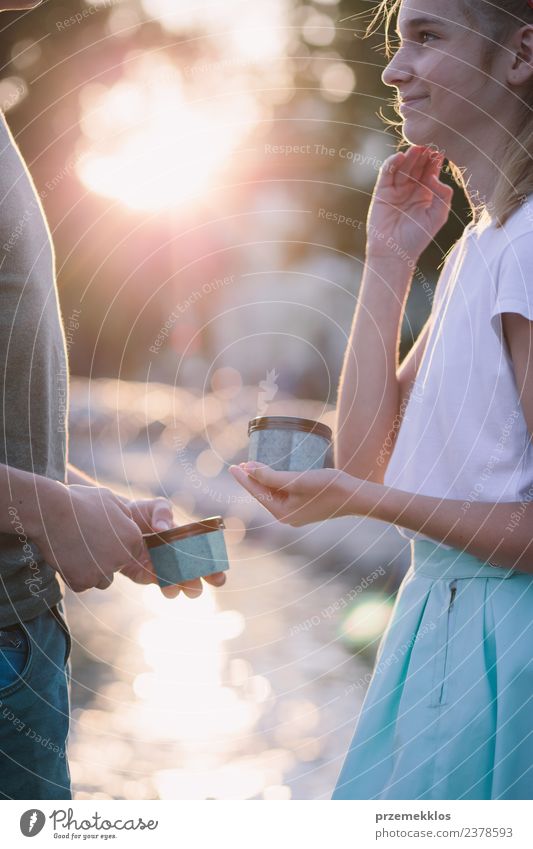 Young teenage girl and boy spending time together in the city centre enjoy eating ice cream on a summer day. Spending quality time on sunny afternoon eating sweet dessert. Downtown area in the background