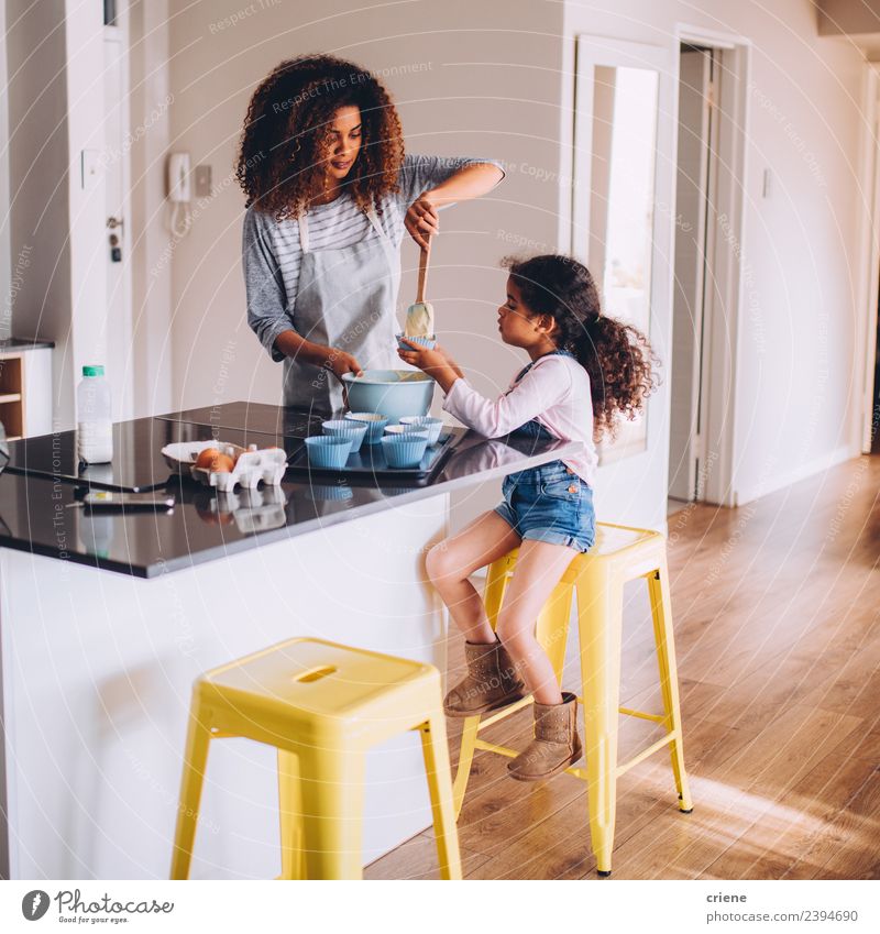 little african girl is helping her mum preparing cupcake dough Dough Baked goods Dessert Joy Happy Beautiful Kitchen Child School Human being Woman Adults