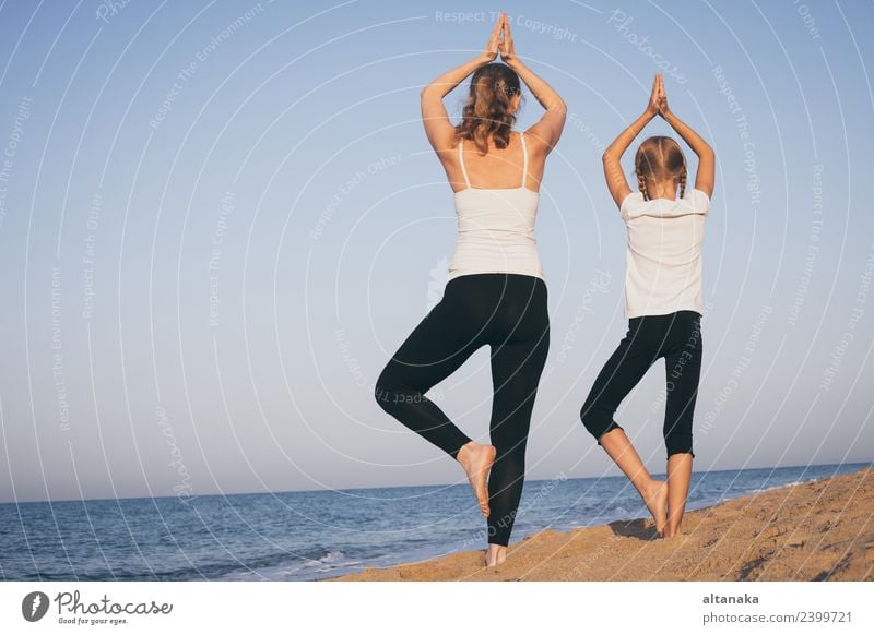 Mother and daughter doing yoga exercises on the beach. Lifestyle Joy Happy Body Wellness Harmonious Relaxation Meditation Leisure and hobbies Camping Summer