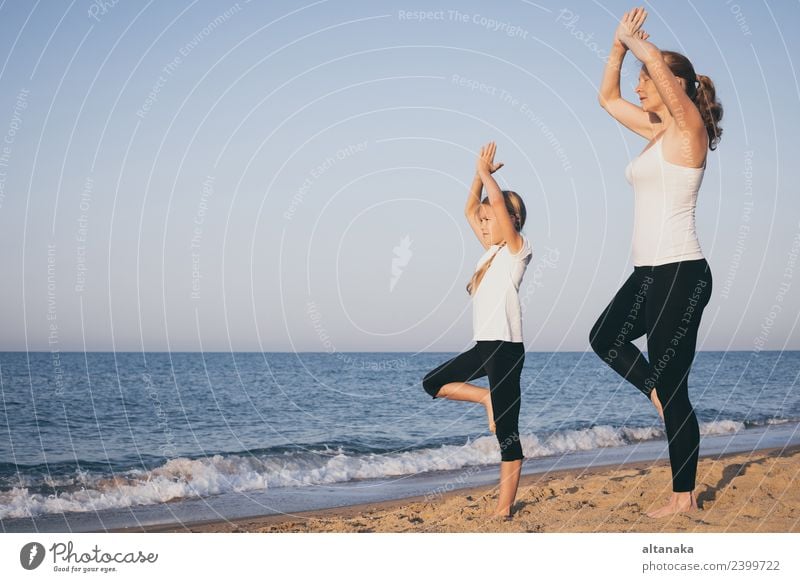 Mother and daughter doing yoga exercises on the beach. Lifestyle Joy Happy Body Wellness Harmonious Relaxation Meditation Leisure and hobbies Camping Summer