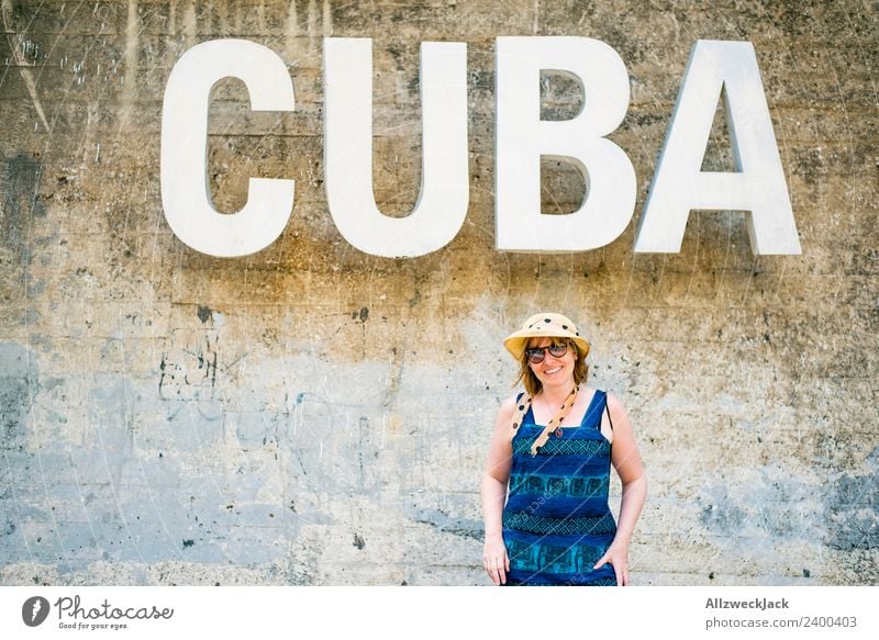 Woman with blue dress and hat before the word CUBA Day Feminine 1 Person Young woman Wall (barrier) Wall (building) Cuba Letters (alphabet) Typography Word