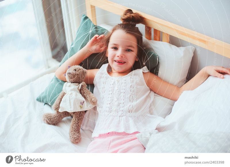 happy child girl wake up in the early morning Lifestyle Joy Happy Hair and hairstyles Relaxation Sun Bedroom Child Toys Teddy bear Smiling Sleep Dream Small