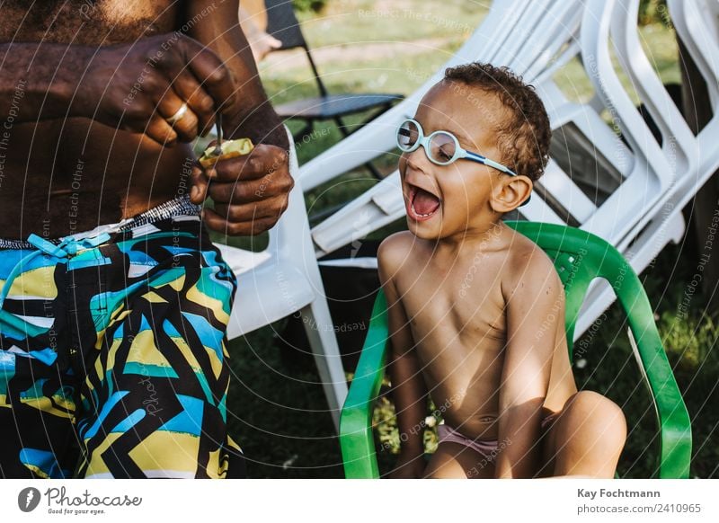 Black father feeds his son a kiwi Fruit Nutrition Eating Spoon Lifestyle Joy Vacation & Travel Summer Summer vacation Garden Child Boy (child) Father Adults