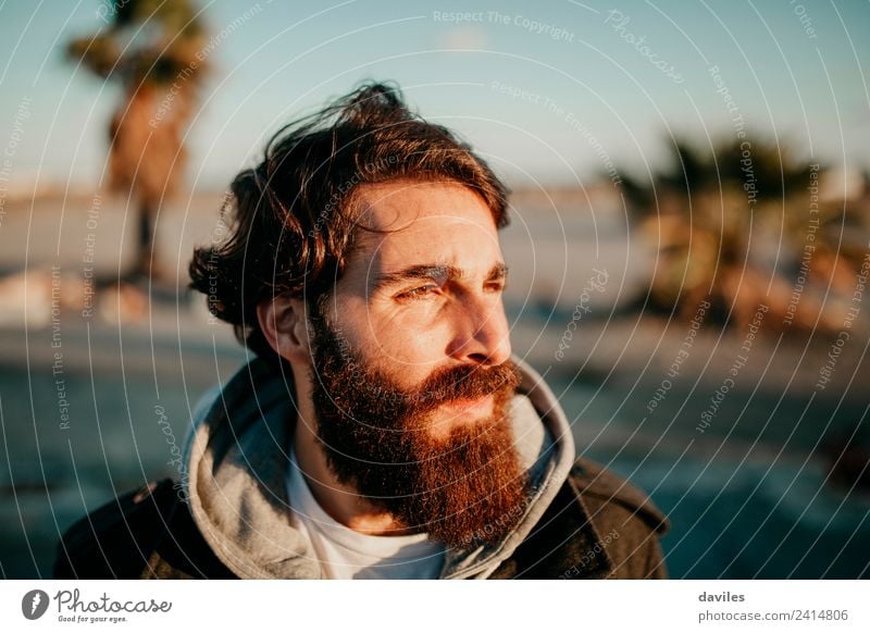 Man with dark hair and long beard posing at sunset with the sun light in his face. Lifestyle Face Calm Human being Masculine Young man Youth (Young adults)